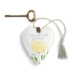 A heart shaped sculpture with a gold key and silver tassel that has a yellow flower says "always and forever".