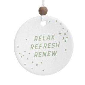 A round white ceramic hanging diffuser that says "Relax Refresh Renew" in green with green dots.