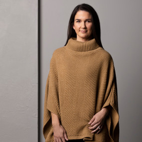 Front facing view of a woman wearing a camel colored cowl neck poncho.