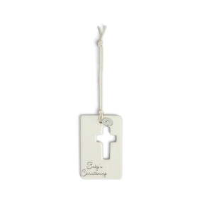 A cream hanging token with a cross cutout and round silver charm with a heart attached to the hanger. The bottom of the token says "Baby's Christening".