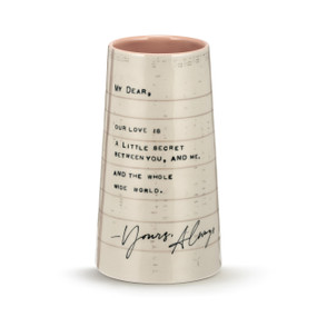 A cream stoneware vase that looks like writing paper and has a loving message on the outside. The interior of the vase is a peach color.