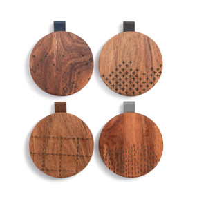 Four different round wood coasters with different patterns on them. They each have a leather tab in a different color on the edge.