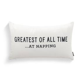 A rectangular white pillow that says "Greatest Of All Time...At Napping" in black.
