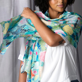 A woman wearing a white blouse and a rectangle scarf loosely around her neck in a floral pattern on a blue and green background inspired by ArtLifting artist Alicia Sterling Beach.