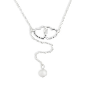 Detail view of the hearts and bead on a thin silver chain necklace with a set of intertwined silver hearts and a small white bead at the bottom.