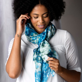 A woman wearing a white top and a blue and green rectangle scarf around her neck, with artwork inspired by ArtLifting artist Mia Brown.