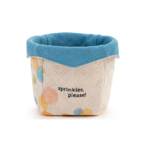A cream fabric ice cream cozy with pastel dots that says "sprinkles, please!" with a blue fabric on the inside.