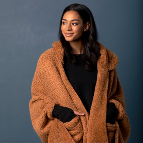 Front view of a woman wearing a hooded camel colored Sherpa wrap with her hands in the front pockets.