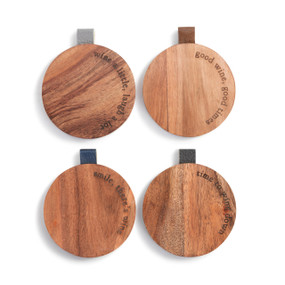 Four different round wood coasters with a wine theme and cute sayings along the edge. They each have a leather tab in a different color on the edge.
