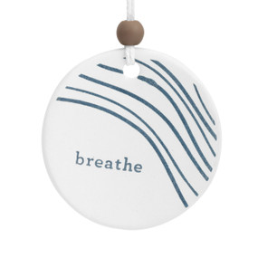 A round white ceramic hanging diffuser with blue wavy lines that says "breathe".
