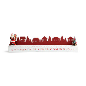 A long rectangular white wood countdown calendar with a red silhouette village behind. The board says "Santa Claus Is Coming" and has a small Santa figure that can be moved down the numbered slots to the Christmas tree at the other end.