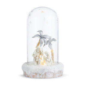 A lit nativity scene inside a glass dome on a faux white wood base.