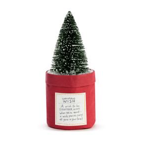 A fake green tree inside a red paper planter that has a tag attached with a message titled "Christmas Wish".