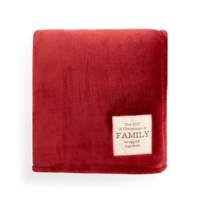 A large red blanket folded and has a fabric tag saying "The JOY of Christmas is FAMILY snuggled together".