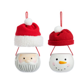 Set of two stoneware ornaments of the faces of Santa and a snowman and suspended above them red fabric hats with white poms.