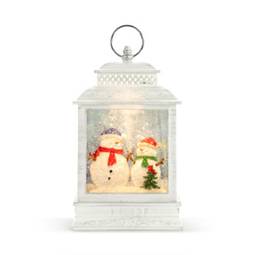 White lit lantern with two snowmen inside by a small tree with a cardinal.