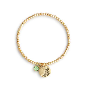 A gold beaded bracelet with a gladiolus flower round charm and light green colored stone.