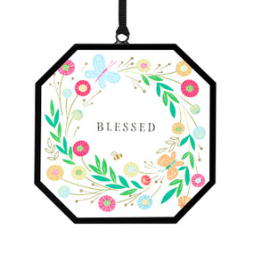 A small octagon shaped sun catcher with illustrated flowers and the saying "Blessed".