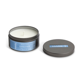 A round dark metal travel tin with a white candle, displayed with the lid off to the side. The candle has a Clear Blue Water scent.