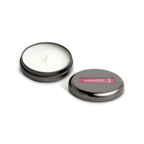 A small round dark metal tin with a white candle displayed with the lid off to the side. The candle has a Currant + Oakmoss scent.