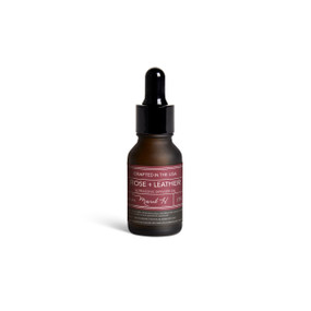 A small dark bottle of Rose + Leather diffuser oil with a black dropper lid.