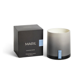 A Clear Blue Water poured candle in an ombre gray glass vessel sitting next to a dark gray packaging box.
