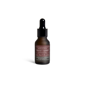 A small dark bottle of Tobacco + Saffron diffuser oil with a black dropper lid.