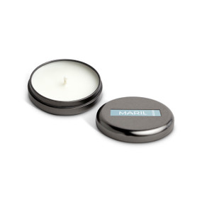 A small round dark metal tin with a white candle displayed with the lid off to the side. The candle has a Coconut + Driftwood scent.