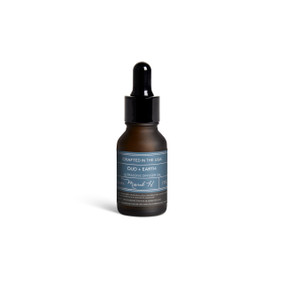A small dark bottle of Oud + Earth diffuser oil with a black dropper lid.
