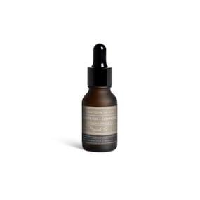 A small dark bottle of White Oak + Cashmere diffuser oil with a black dropper lid.