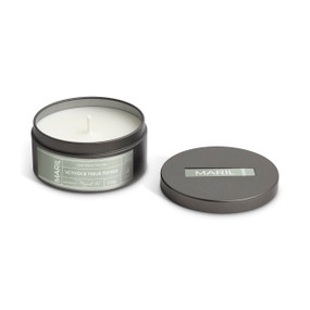 A round dark metal travel tin with a white candle, displayed with the lid off to the side. The candle has a Vetiver + Timur Pepper scent.