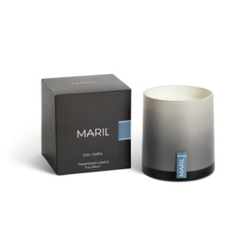 An Oud + Earth poured candle in an ombre gray glass vessel sitting next to a dark gray packaging box.