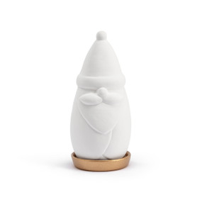 A white ceramic diffuser shaped like a gnome resting in a round gold shallow dish.