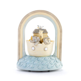 A musical sculpture of Noah's Ark with the animals on blue water with a three color rainbow going over the top.