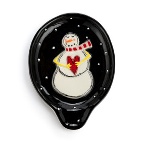 A black stoneware spoon rest with white dots and a raised white snowman and a red heart.