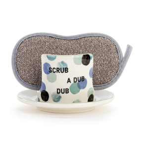 A cream ceramic soap dish that says "Scrub A Dub Dub" on the front with large blue and green dots, and a gray sponge in the open slot.