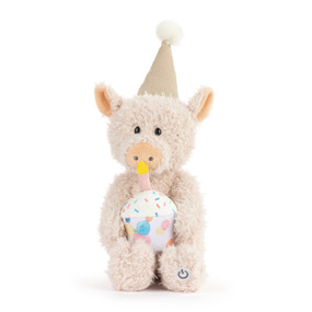A plush light pink pig wearing a birthday hat and holding a plush confetti cupcake with a candle. The pig sings when you push the button on its foot.