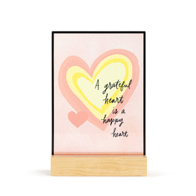 A large rectangular suncatcher in a light wood base. The image is a pink and yellow heart and the saying "A grateful heart is a happy heart".