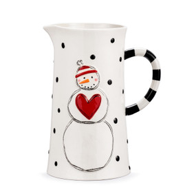 A white ceramic pitcher with black dots and a raised white snowman with a red heart on his chest.