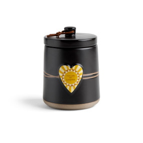 A round black ceramic poured candle with a tan textured base, a lid and a yellow raised heart on the front with a sun illustration and the words "You Are My Sunshine".