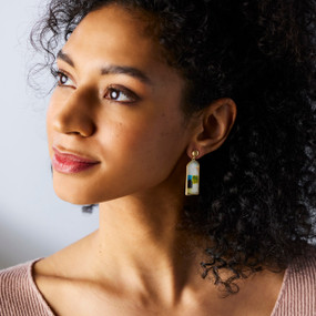 A woman wearing a pair of earrings with a vertical rectangle of colored squares on white.