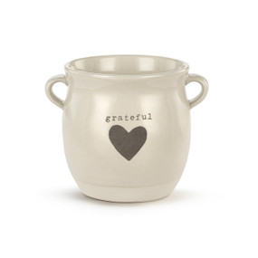 A cream ceramic planter with two small handles on the sides. The planter says "grateful" and has a gray heart on the front.