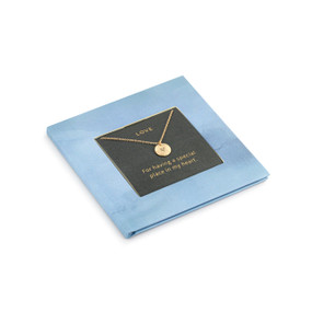 A small square blue book with inspirational content about love. There is a gold chain necklace inside with a round charm.