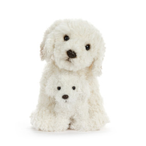 A white plush adult labradoodle dog sitting with a white labradoodle puppy between its paws.