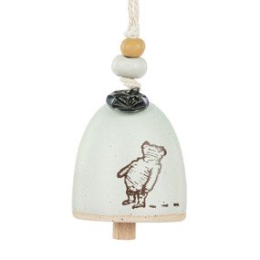 A mini cream bell with an image of Pooh looking up. There are beads and a metal token at the top of the bell.