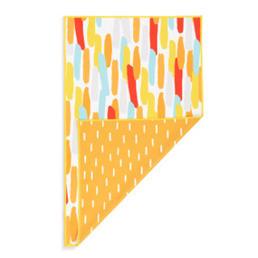 A rectangular double sided towel. One side is orange with white lines and the other is white with multicolored lines, displayed with the orange corner turned back.