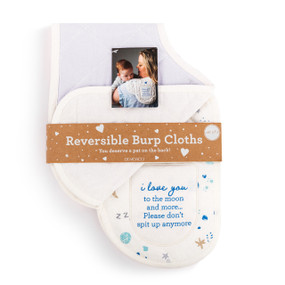 A set of two burp cloths in light gray and white. One is light gray and the other has a planets and stars illustration and says "i love you to the moon and more...Please don't spit up anymore", displayed in a packaging band.