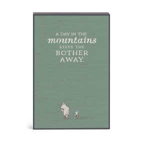 A green wall art with an illustration of Pooh and Piglet and the saying "A day in the mountains keeps the bother away."