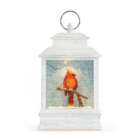 A white lit musical lantern with the image of a red cardinal on a branch inside.