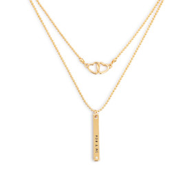 Detail view of the charms on an adjustable gold layered necklace with intertwined hearts on one layer and a band that says "You & Me" on the other.